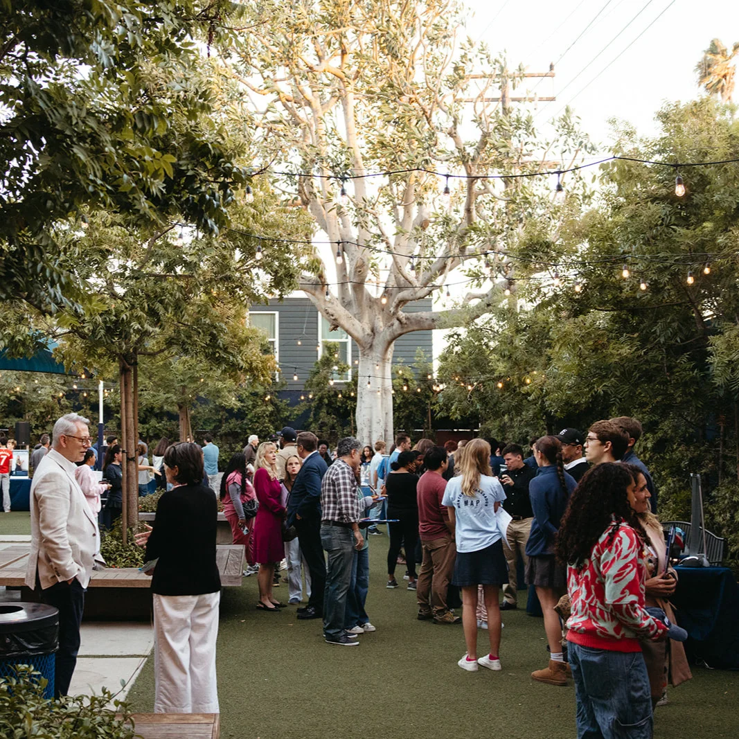 People mingling at an outdoor courtyard event under string lights.